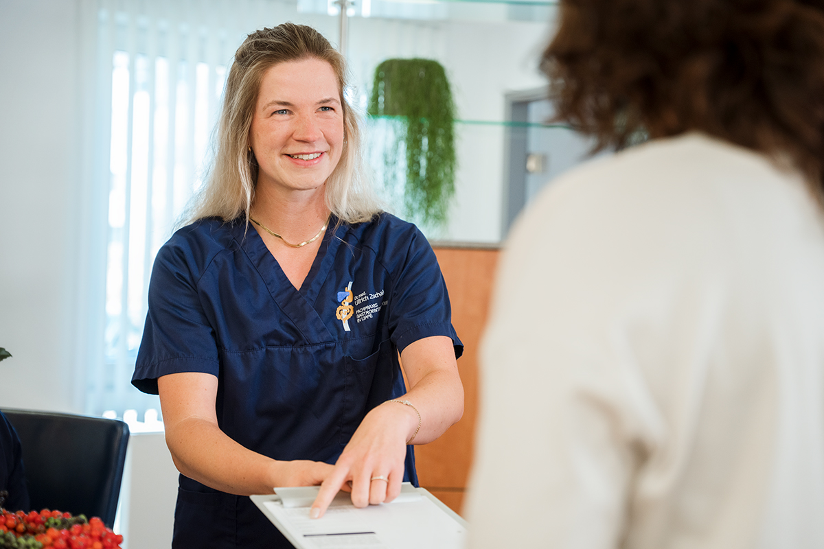 Eine Arzthelferin zeigt auf eine Information auf einem Klemmbrett