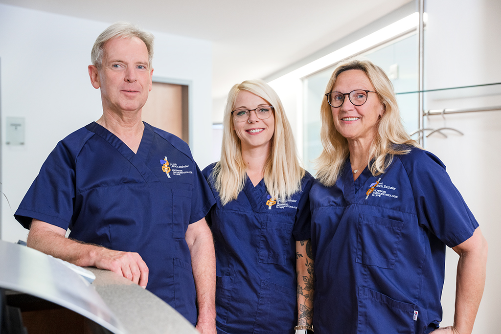 Dr. med. Ullrich Zschaler mit zwei seiner Mitarbeiterinnen am Empfangstresen seiner Praxis