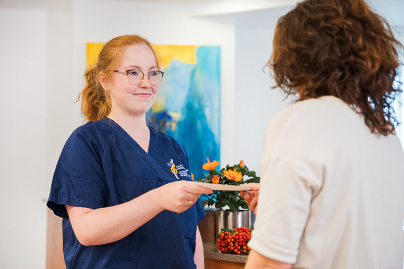 Eine Medizinische Fachangestellt überreicht einer Patientin ein Rezept.